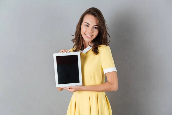 Menina bonita no vestido mostrando computador tablet tela em branco — Fotografia de Stock