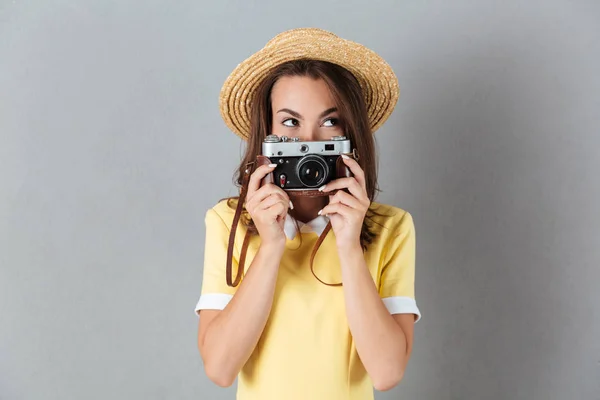 Όμορφη νεαρή κοπέλα με καπέλο κρατώντας vintage φωτογραφική μηχανή στο πρόσωπό της — Φωτογραφία Αρχείου