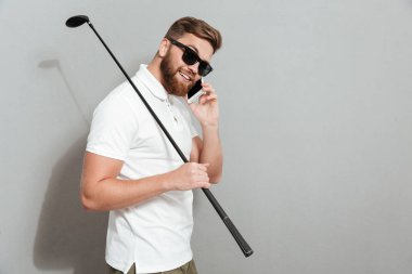 Konuşmak smartphone tarafından güneş gözlüğü sakin golfçü yan görünüm