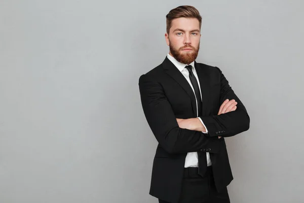 Confident young businessman in suit standing with arms folded — Stock Photo, Image