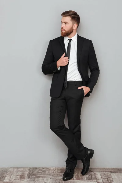 Elegante hombre de negocios guapo en traje posando mientras está de pie —  Fotos de Stock