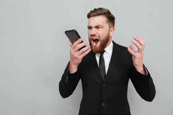 Evil bearded man in suit screaming in his smartphone — Stock Photo, Image