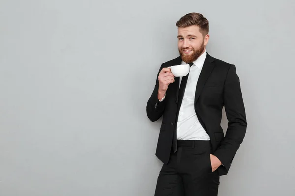 Плідна прохолодна бородата людина в костюмі п'є чай — стокове фото