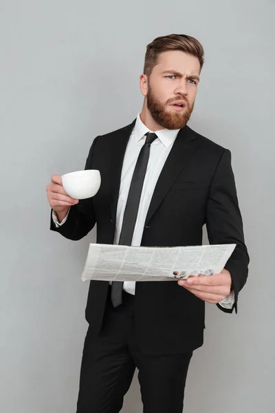 Jeune homme d'affaires en costume tenant journal et tasse de café — Photo