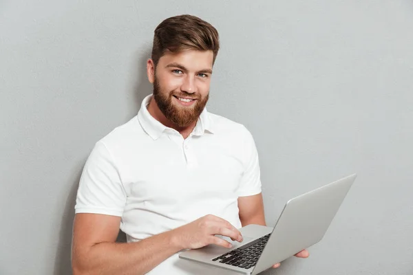 Dizüstü bilgisayar kullanan sakallı adam gülümseyen — Stok fotoğraf