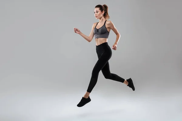 Vista lateral retrato de longitud completa de una joven mujer de fitness corriendo — Foto de Stock