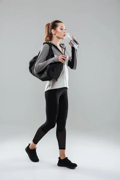 Joven bonita mujer de fitness que lleva bolsa de deporte y agua potable — Foto de Stock