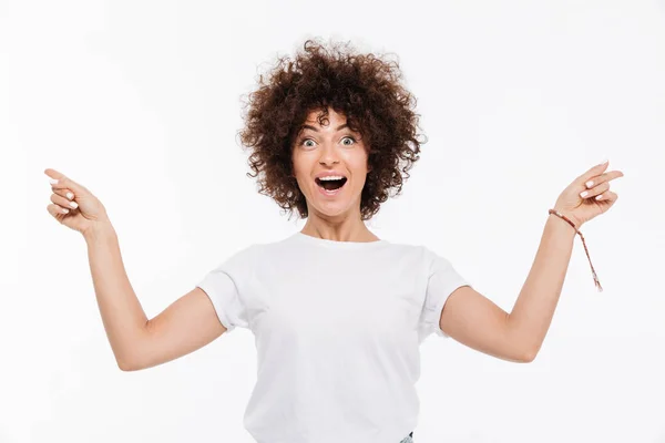 Feliz mujer excitada con el pelo rizado señalando los dedos hacia los lados —  Fotos de Stock