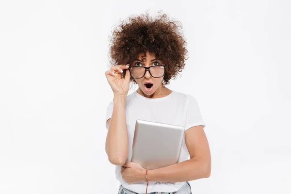 Mujer casual conmocionada sosteniendo la tableta de PC y mirando por encima de las gafas —  Fotos de Stock