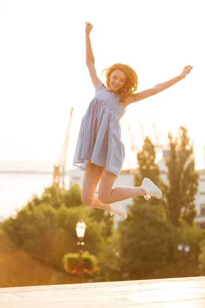 Happy young girl in dress jumping outdoors — Stock Photo, Image