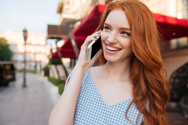 Glimlachend aantrekkelijk meisje met lang haar praten op mobiele telefoon — Stockfoto