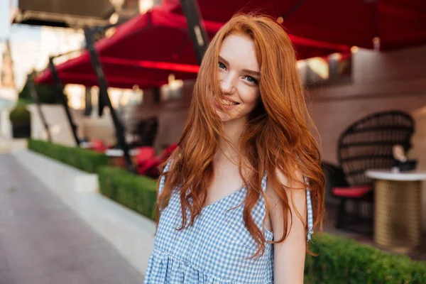 Улыбающаяся рыжая девушка с длинными волосами, смотрящая в камеру — стоковое фото