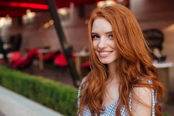 Красивая рыжая девушка с длинными волосами смотрит в камеру — стоковое фото