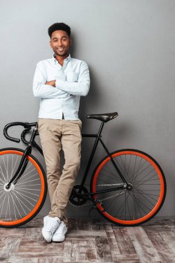 Genç Afrika adam bisiklet ile gri duvarın üzerinden ayakta.