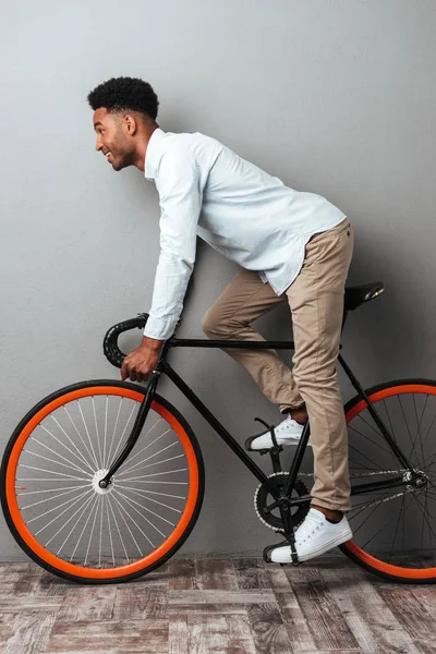 Genç Afrika adam bisiklet ile gri duvarın üzerinden ayakta.