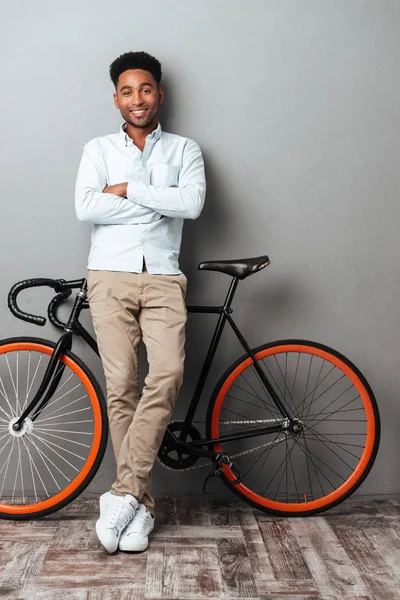 Genç Afrika adam bisiklet ile gri duvarın üzerinden ayakta.