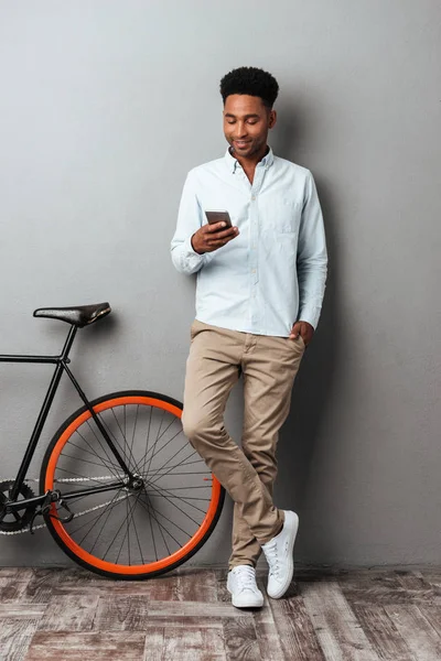 Neşeli genç Afrika adam gri duvar sohbet üzerinde ayakta