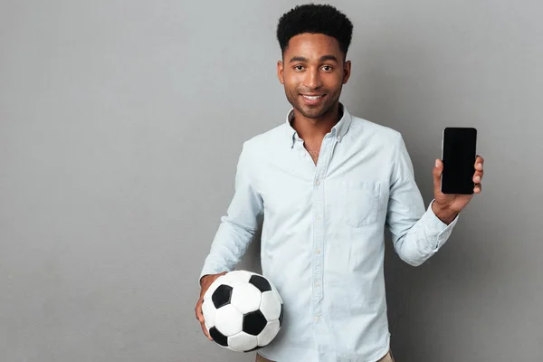 Man showing blank screen mobile phone and holding football — Stock Photo, Image