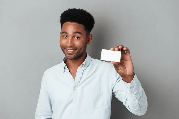Sonriente joven afro-americano sosteniendo tarjeta de visita en blanco — Foto de Stock