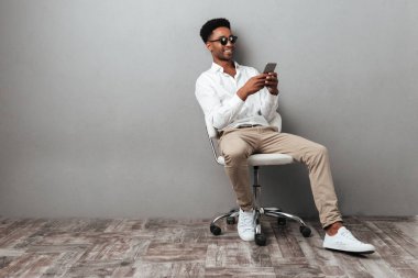 Bir sandalyede oturuyor ve cep telefonu tutan adam