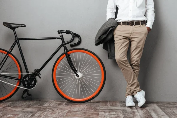 Одетый наполовину мужчина стоит рядом с велосипедом — стоковое фото