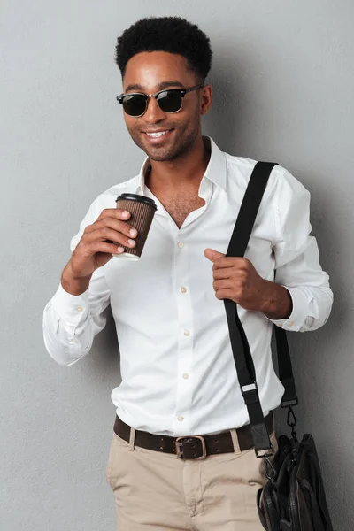 남자는 가방을 착용 하 고 커피 컵을 들고 선글라스 — 스톡 사진
