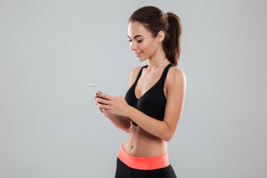 Smartphone kullanarak gülümseyen bir fitness kadın yan görünüm
