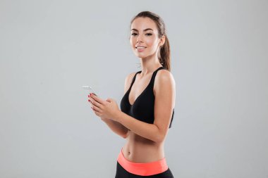 Smartphone tutan gülümseyen bir fitness kadın yan görünüm