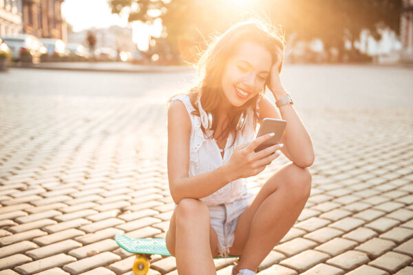 Молодая женщина сидит на скейтборде на открытом воздухе
