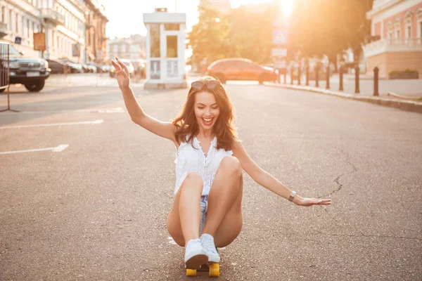 Smiling young woman on skateboard outdoors — Stok Foto