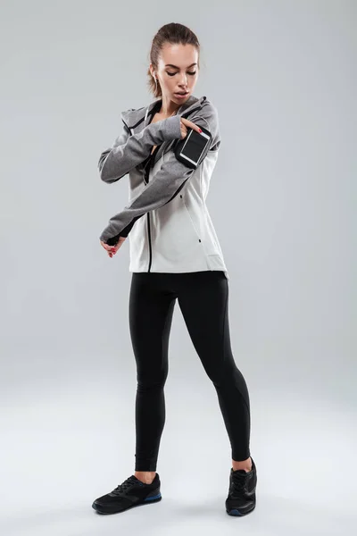 Imagem completa de uma mulher esportiva usando smartphone — Fotografia de Stock