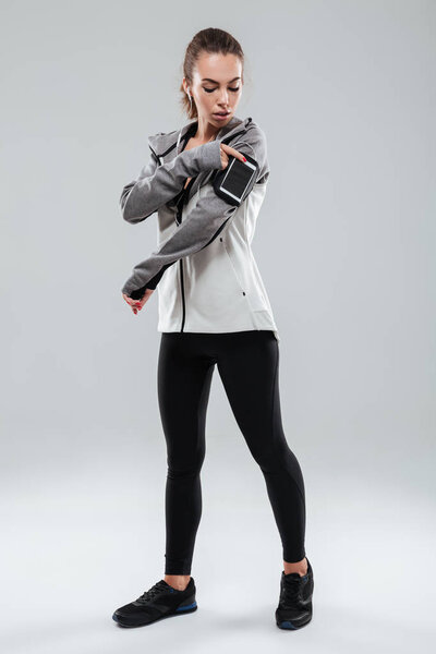 Full length image of a sports woman using smartphone