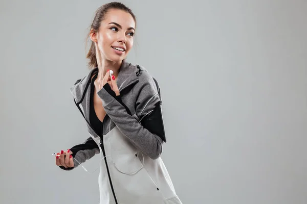 Corredor feminino sorridente em roupas quentes ouvindo música — Fotografia de Stock