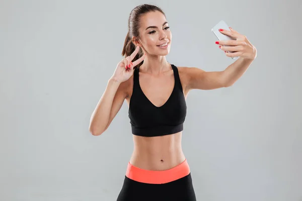 Улыбающаяся фитнес-женщина делает селфи на своем смартфоне — стоковое фото