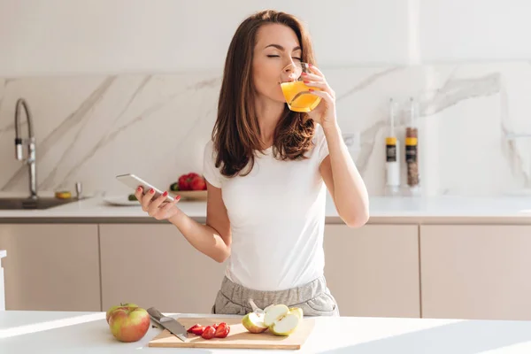 Jovem mulher alegre bebendo suco de laranja — Fotografia de Stock