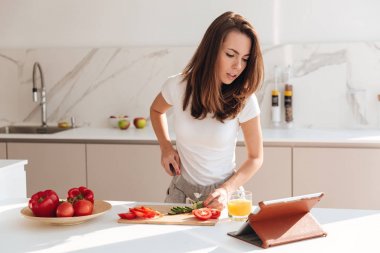 Genç kadın kesme sebze bir ahşap tahta üzerine konsantre