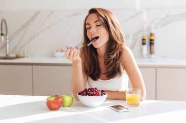 Genç ve güzel kadın bir kaseden meyveleri yemekten hoşlanır