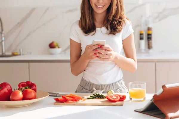 Обрезанное изображение красивой улыбающейся женщины с помощью мобильного телефона — стоковое фото