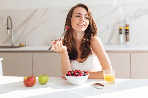 Sorrindo mulher feliz comendo frutas frescas de uma tigela — Fotografia de Stock