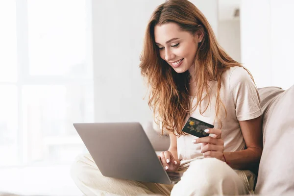 Jeune femme travaillant avec ordinateur portable et carte de crédit à la maison — Photo