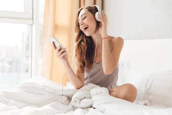 Bella dama escuchando música en la cama en casa — Foto de Stock