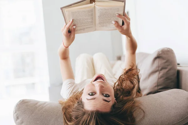 Schot van grappige vrouw liggend op Bank met boek — Stockfoto