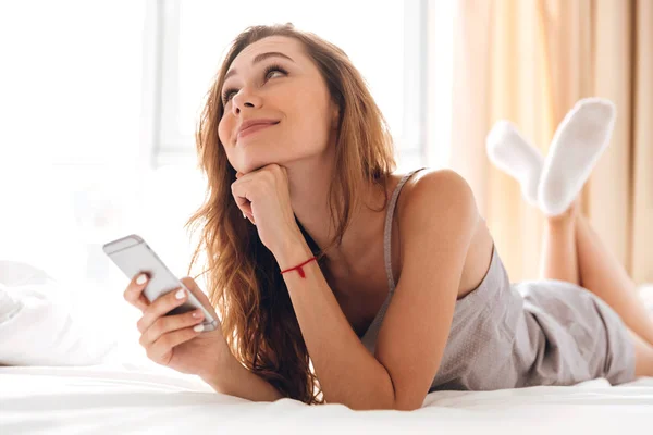 Feliz emocional hermosa dama se encuentra en la cama charlando por teléfono . — Foto de Stock