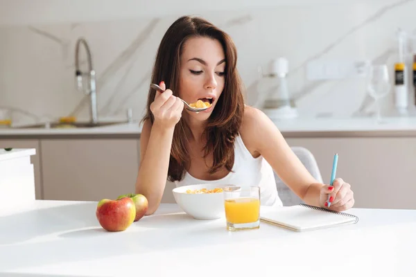 Mujer joven ocasional comiendo cereales en copos de maíz para el desayuno — Foto de Stock