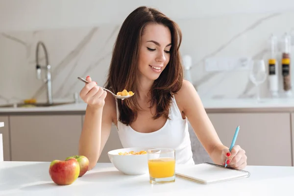 Attractive healthy woman eating corn flakes cereal for breakfast