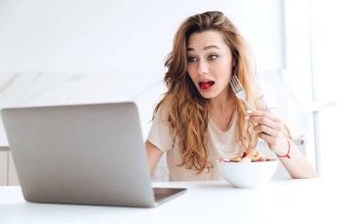 Yeme ve dizüstü bilgisayar kullanarak sürpriz kadın