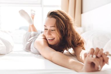 Genç kadın yatakta uzanan gülüyor