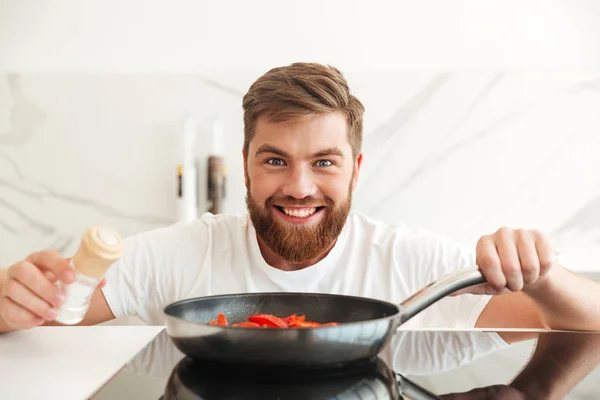 野菜の調味料を振りかける男のひげを生やした笑顔 — ストック写真