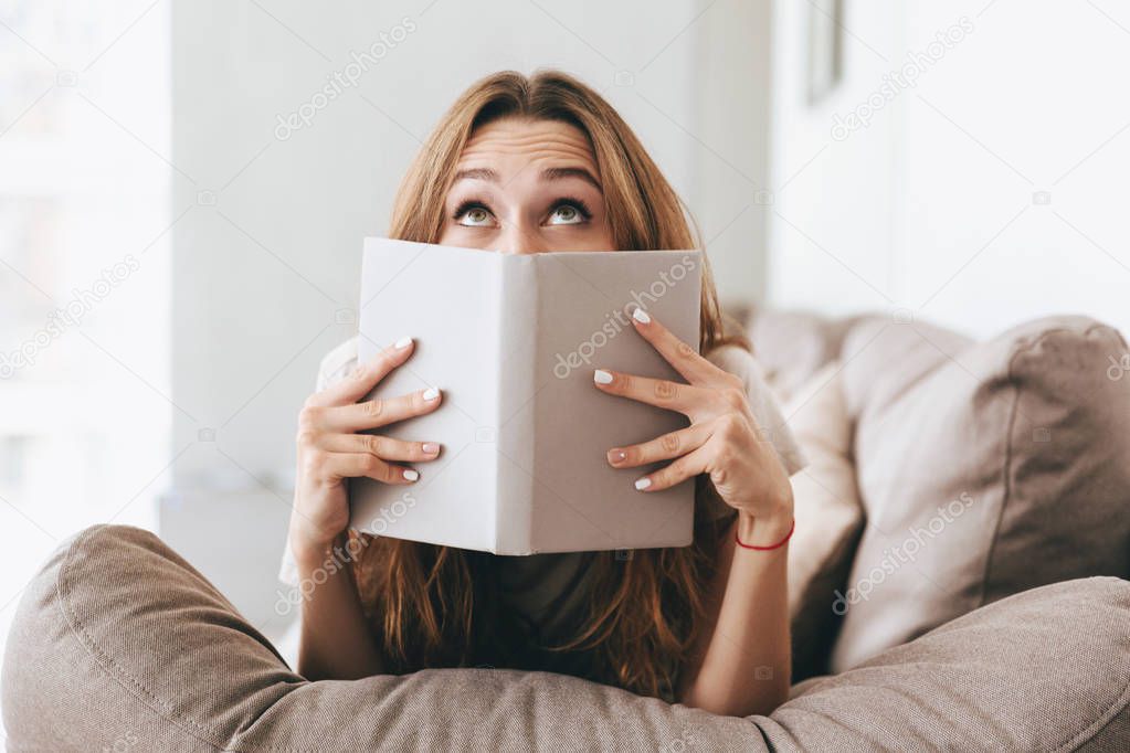 Pretty lady covering face with book.
