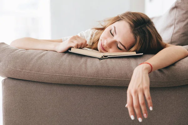 Stanca donna rilassata dormire con libro sul divano — Foto Stock